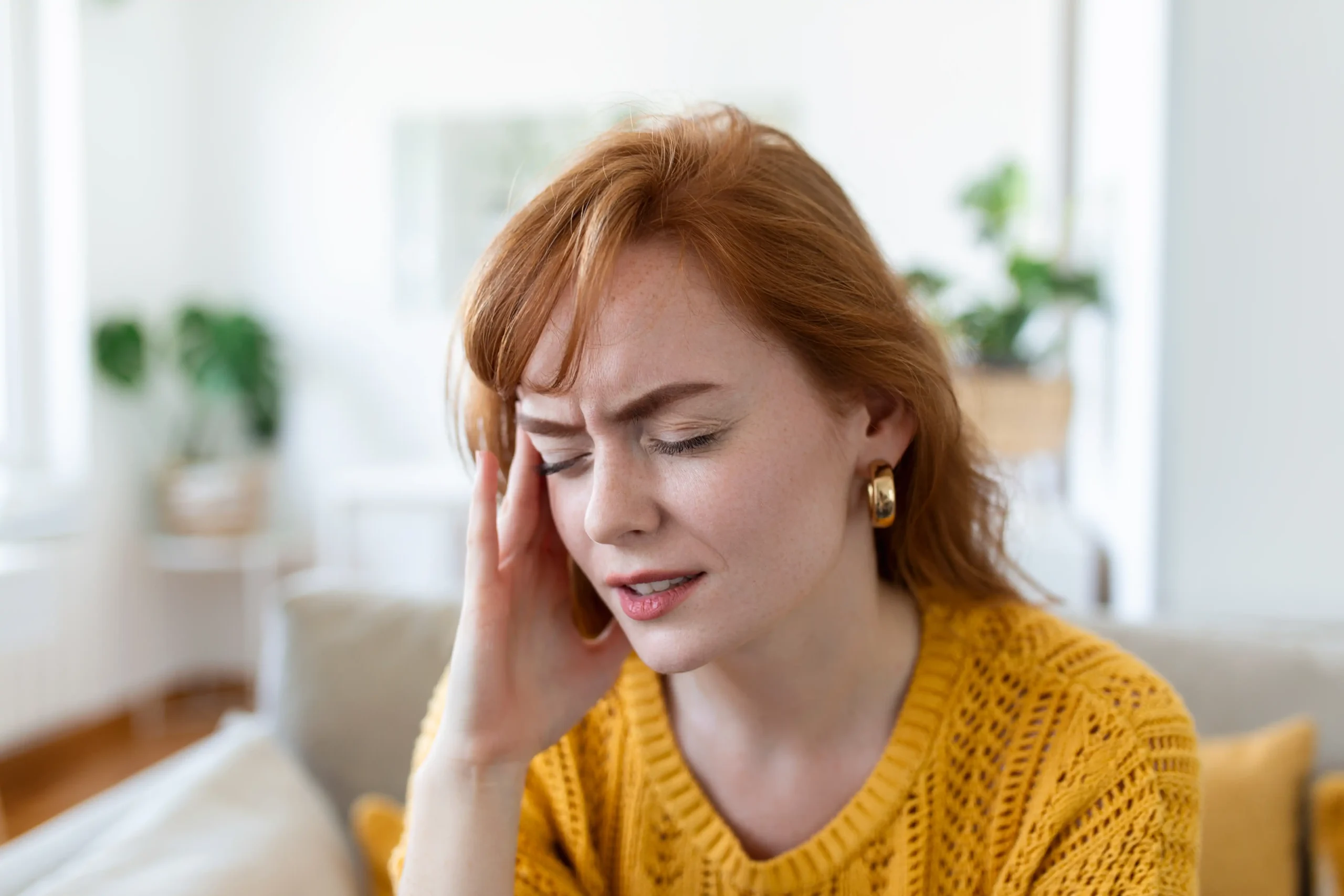 Woman outdoors holding her head in pain