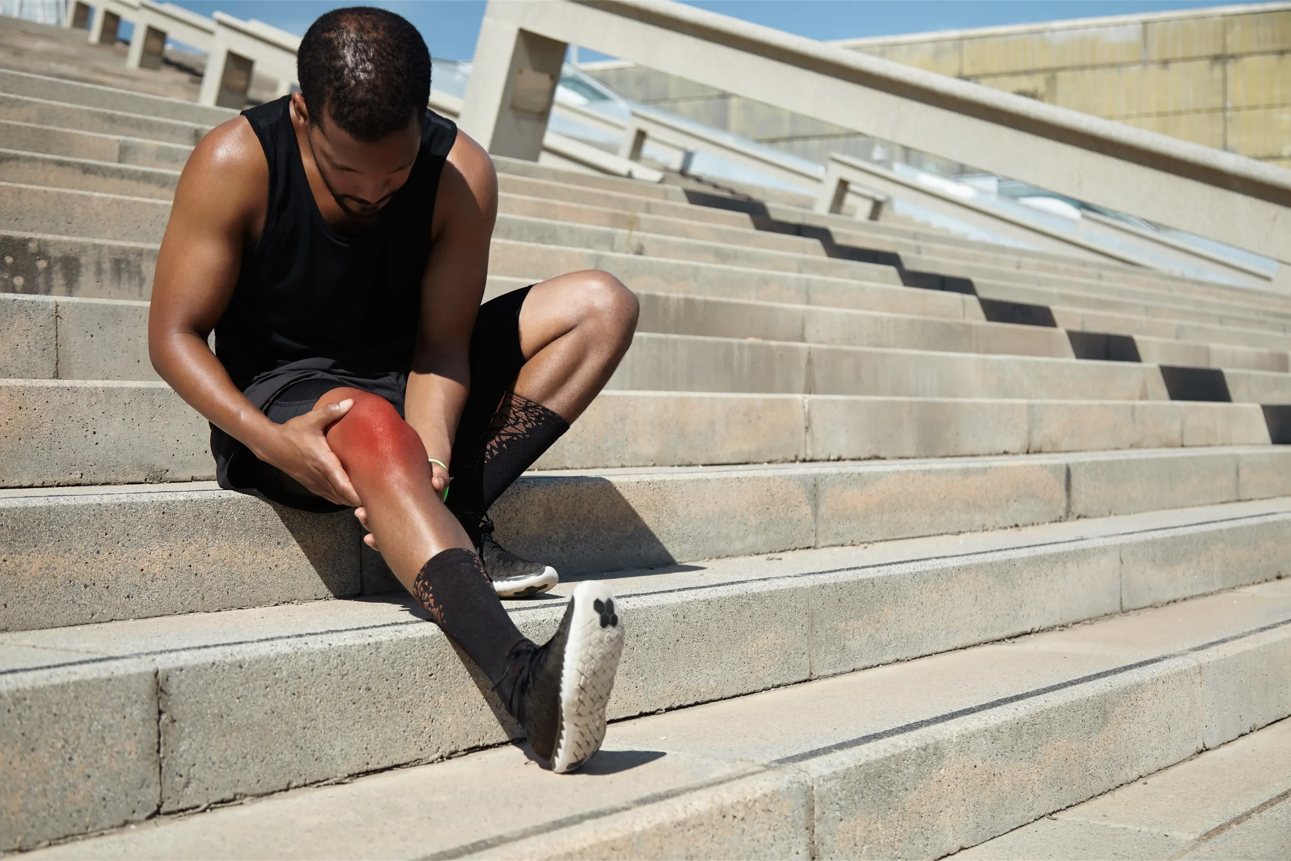 Person sitting outdoors holding their ankle